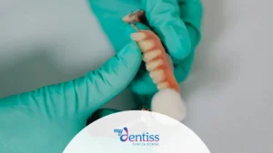 Imagen de un dentista con guantes verdes de látex sostiene una prótesis dental parcial de color rosa y blanco que muestra varios dientes, utilizada como fondo en un blog de MyDentiss